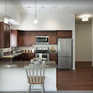 A modern kitchen featuring wooden cabinets, granite countertops, and stainless steel appliances.