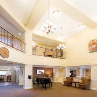 A spacious lobby with a grand piano, chandelier, and seating area.