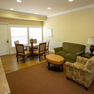 A cozy living room with a dining area featuring a sofa, armchair, and dining table.