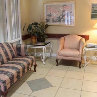 A cozy waiting room with a striped sofa, a pink chair, side tables, and decor.
