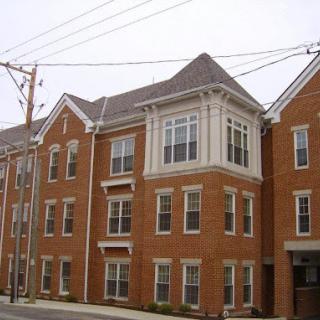 A modern brick apartment building featuring multiple levels and large windows.