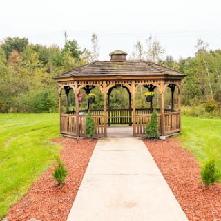 A charming wooden gazebo surrounded by lush greenery and a well-maintained pathway.