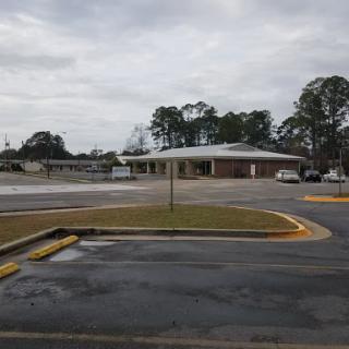 A view of an unoccupied parking lot next to a building under a cloudy sky.
