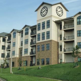 A modern residential apartment complex featuring a prominent clock tower.