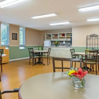 A well-lit dining area with multiple tables and chairs, decorated with small vases of flowers.