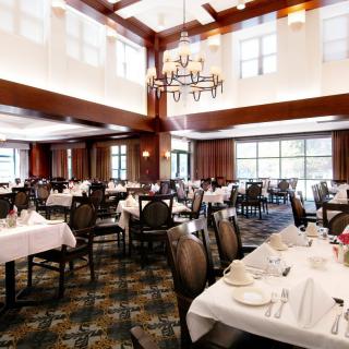 An elegant restaurant dining area with neatly arranged tables and a chandelier lighting up the room.