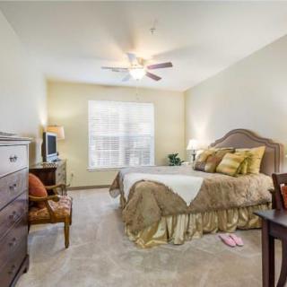 A cozy bedroom with a bed, ceiling fan, and warm lighting.