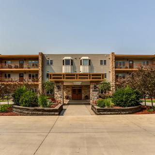 A multi-story residential apartment building with a landscaped entrance and driveway.