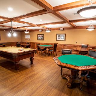 A cozy game room featuring a billiards table and poker tables, designed for leisure and entertainment.