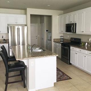 A modern kitchen with white cabinets, an island, and stainless steel appliances.