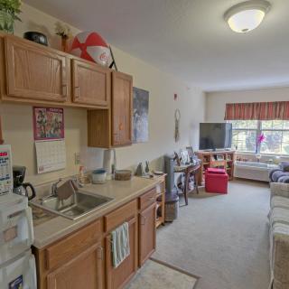 A cozy apartment with a compact kitchen area leading into a living room with a television.