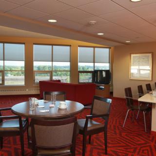 A modern conference room with a round table, chairs, and large windows.