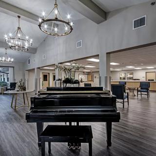 A spacious lobby featuring a grand piano and elegant chandeliers.