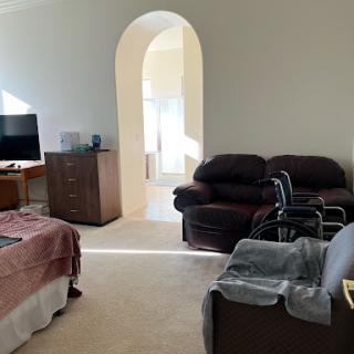 A cozy living room featuring a sofa set, television, and an arched doorway allowing natural light.