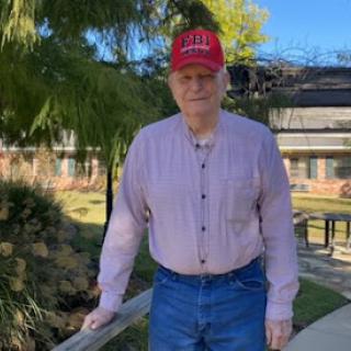 A man enjoying a sunny day outdoors, dressed casually with a hat.