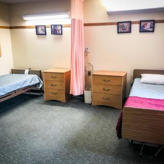 A hospital room with two beds separated by a privacy curtain.