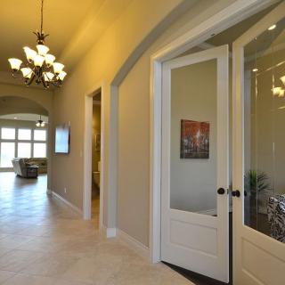 Spacious hallway with elegant lighting and a view into a bright room.