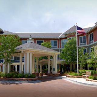 A well-maintained building entrance with a flagpole and surrounding greenery.