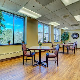 A bright and inviting office space featuring tables and chairs, bathed in natural light from large windows.