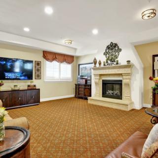 A cozy living room featuring a fireplace and a large television, furnished with comfortable seating and warm decor.