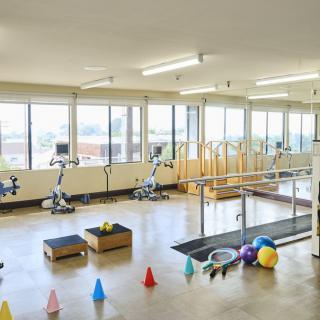 A spacious rehabilitation gym with various exercise equipment, including stationary bikes and therapy tools.