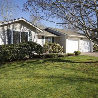 A suburban house with a well-maintained lawn and a driveway under a clear blue sky.