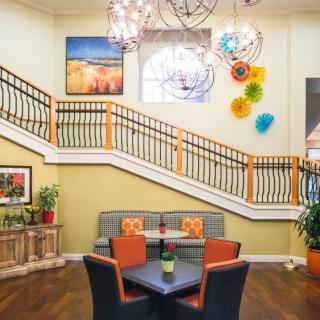 A modern lobby featuring colorful artwork, unique lighting fixtures, and comfortable seating beside a staircase.