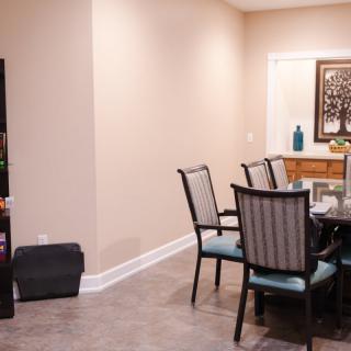 A cozy dining room with a glass-top table and upholstered chairs.