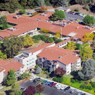 An aerial view of a residential complex surrounded by trees and a parking lot, showcasing the vibrant colors of autumn.