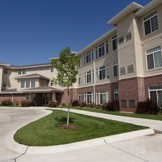 A modern three-story apartment complex with well-maintained landscaping and a circular driveway.