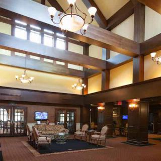 A spacious lobby with high ceilings, featuring wooden beams and elegant chandeliers, includes a comfortable seating area.