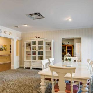 A cozy dining room with a white table and chairs, surrounded by elegant furnishings and warm lighting.