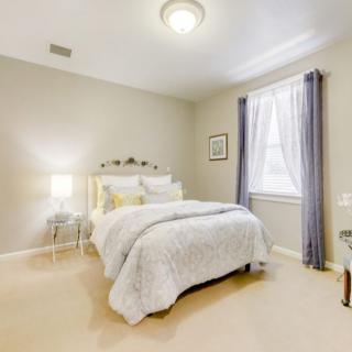 A cozy bedroom with a neatly made bed and soft lighting.