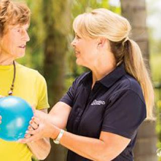 Two women engaging in an outdoor fitness activity with a ball.