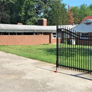 A suburban house with a brick wall, driveway, and metal gate.