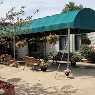 A welcoming outdoor seating area with a green awning and beautiful flower arrangements.