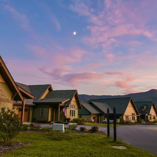 A picturesque neighborhood with beautiful houses against a sunset sky and mountains in the background.