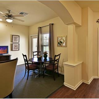 A cozy dining area with a round table and chairs, accented by warm lighting and elegant decor.