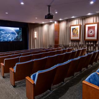 A small, cozy indoor movie theater with several rows of seating facing a projection screen.