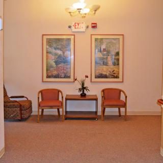 A cozy waiting area with two chairs, a small table, and decorative artwork on the wall.