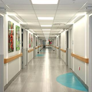 A brightly lit hospital corridor featuring colorful artwork on the walls.