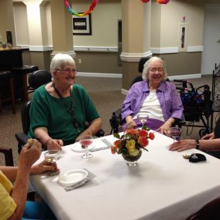 A group of seniors enjoying a conversation around a dining table.