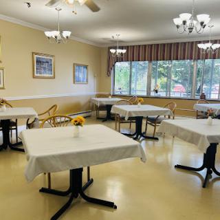 A spacious dining area featuring neatly arranged tables and chairs, illuminated by soft lighting.