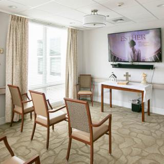 A neatly arranged meeting room with chairs facing a large television on the wall.
