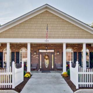 A charming house entrance with a brick fa�ade, white columns, and a decorative front door.