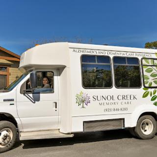 A community service bus from Sunol Creek parked under a clear blue sky.