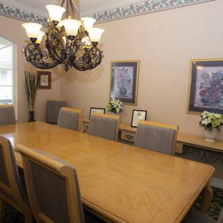 A well-appointed dining room featuring a large wooden table, elegant chandelier, and framed artwork.