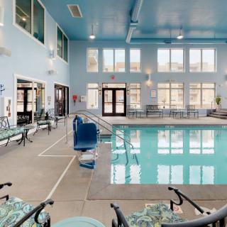 An indoor swimming pool area with chairs and large windows.