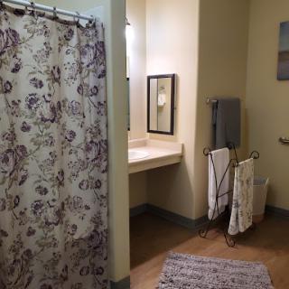 A cozy bathroom featuring a floral shower curtain and neatly arranged towels.