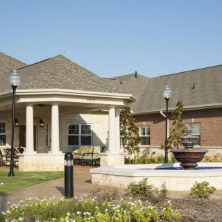 A suburban-style building with a garden and fountain in the foreground.
